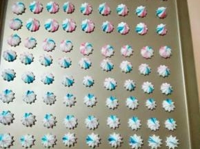 4、用牙签蘸取少量的色素，涂抹在裱花袋里，然后装入蛋白糊，挤在烤盘上，这时预热烤箱100度10分钟。