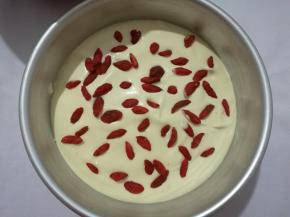 蛋糊倒入模具一半时，撒上一层枸杞子。