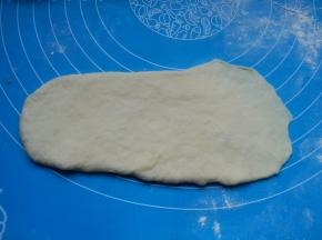 取一个松弛好的面团，擀成长舌形，一边擀薄。
