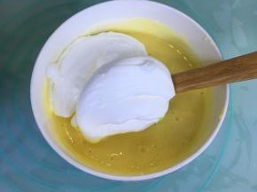 取三分之一的蛋白霜到蛋黄糊里，用刮刀翻拌均匀。