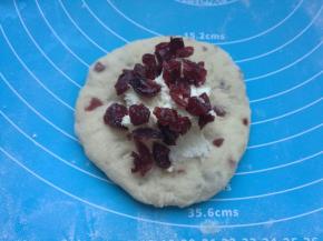 松弛好的面团擀成圆片，包入芝士馅，再撒上几粒蔓越莓。