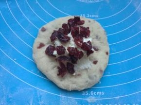 松弛好的面团擀成圆片，包入芝士馅，再撒上几粒蔓越莓。