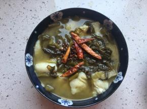 将花椒和干辣椒放在酸菜鱼表面