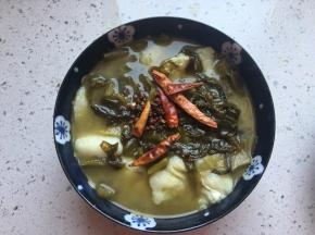 将花椒和干辣椒放在酸菜鱼表面