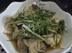 10. 蒸到12分钟时把调味菜码在鱼面上，最后加上一勺花生油，盖上盖子，再蒸一分钟，即可出锅