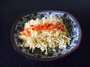 把炸好的蒜米均匀地铺在金针菇上，把蒜油浇到金针菇上。小米椒圈撒在金针菇上，不吃辣的小伙伴们忽略这步。