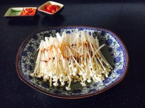 金针菇去除老根，洗干净，沥干水分，放在盘中，撒上少许盐，淋上少许蒸鱼豉油。