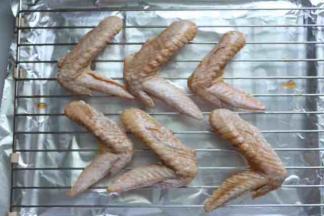 稍微给鸡翅按摩几分钟让调料更好吸收，盖上保鲜膜盖放入冰箱腌制至少3小时或者放一夜，然后，烤盘上垫上锡纸，上面再放上烤网，将鸡翅放在烤网上