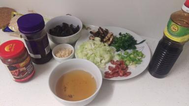 提前把花菇泡水，切4片，香菇水留住。洋葱切小丁，葱切小段。腊肠切小段，黑木耳切宽的一条一条。把豆瓣酱+甜面酱+黑酱油+糖+香菇水调成一碗料