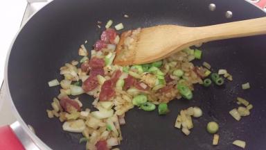 加入腊肠和葱头，炒一下