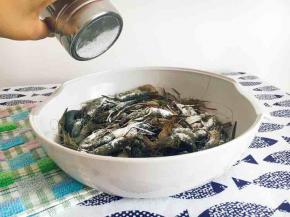 筛入淀粉，晃动盆子，使小河虾均匀裹上淀粉。