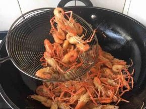 当用笊篱盛出小河虾，轻轻的颠勺，听到有沙沙的响声时就可以把小河虾捞出来。