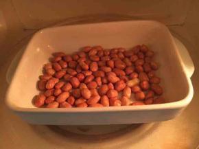 花生米洗净，放在水里泡5分钟左右，然后用厨房餐巾纸吸干水份，放在一个容器里，喷上油，用微波炉加热1分钟3次。刚刚加热好的花生米要放置一段时间，凉透了才脆爽。我一般都是提前一天做好一小盘花生米，随用随取。还有就是每家微波炉的脾气不同，因此加热的时间也会不同。