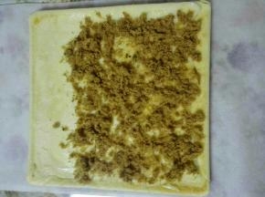 6、烤好后出炉震两下放凉，准备一张油纸，比蛋糕体长一点，底面朝上，抹上沙拉酱，撒上肉松(我自己炒的牛肉松)。