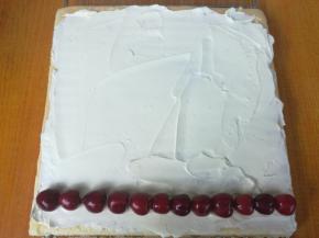 用抹刀铺在蛋糕卷背面，放入一排洗净晾干的樱桃。