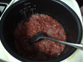 然后将白砂糖和搅拌好的草莓倒入电饭锅里煮