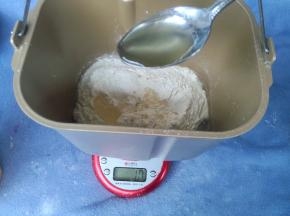 取出冷藏好的面团，撕成小块，放入面包机，加入主面团蛋液、盐，全麦粉、奶粉，再加入蜂蜜10克。