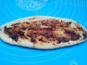 取一个小面团，擀成牛舌状，涂上老干妈辣酱。