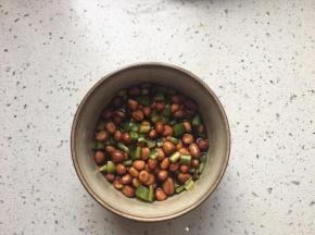 将花生米和青椒加到料汁碗内，拌匀。放到冰箱冷藏半小时