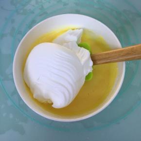 取三分之一的蛋白霜到蛋黄糊里，用刮刀翻拌均匀。