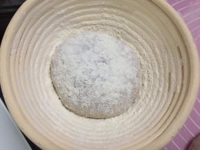 将洛可可面团排气后收紧成圆形，放入发酵篮里，表面撒上手粉轻轻按压