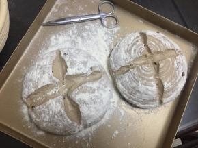 醒发好后将面包篮里的面团倒扣在烤盘里，用剪刀剪开，撒上面粉
