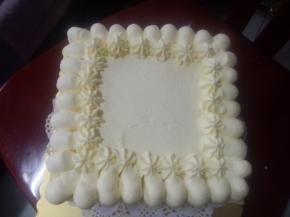 再盖上最后一片蛋糕片。抹上薄薄的一层奶油（家人都不喜欢吃奶油所以用的少），在周围挤上一圈，换八齿裱花嘴在周围挤上一圈小花。