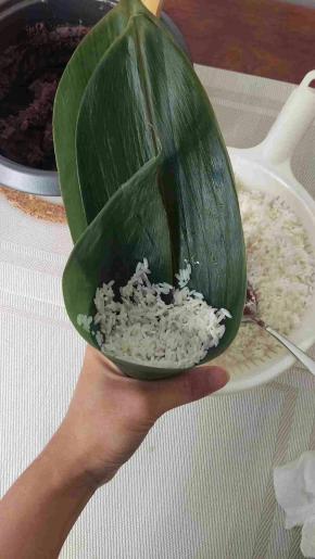 放一点糯米在粽子底部。叶子边缘也是要放点。不要放太多在底部。



