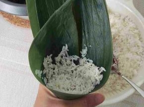 放一点糯米在粽子底部。叶子边缘也是要放点。不要放太多在底部。




