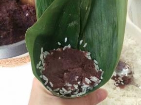 再放上一团豆沙，自己看要包多少都 可以，不要太多，因为上面还要再盖一层糯米。放好后轻轻压一压豆沙。
