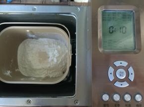 材料内除黄油外按照先液体后固体，最后面粉挖坑放酵母，启动面包机和面程序10分钟。