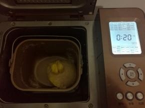 和面结束，静置8分钟。加入切成小块室温融化的黄油，再次启动面包机和面程序20分钟。