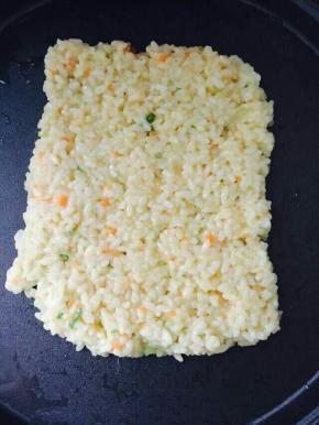 搅拌好的米饭放饼铛上拍平小火煎。