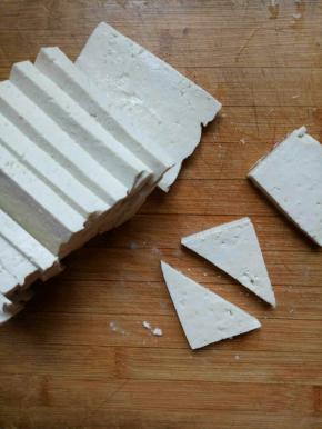 老豆腐用开水烫一下切大约0.5厘米左右厚的薄片，然后再切成三角形