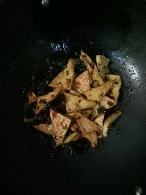 再加入豆腐和木耳翻炒，加入适量的清水和1茶匙白糖炒匀，烧开入味