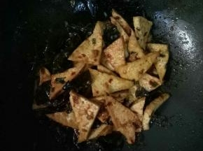 再加入豆腐和木耳翻炒，加入适量的清水和1茶匙白糖炒匀，烧开入味