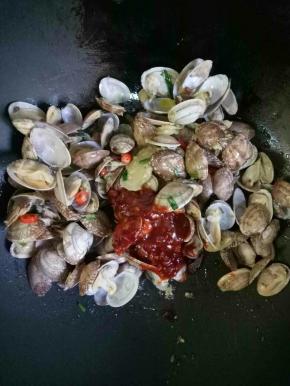 加入料酒2茶匙，糖2茶匙，郫县豆瓣酱2茶匙，翻炒均匀即可关火（因为花甲已经基本熟了，不能太长时间翻炒，肉容易老，炒的时间最好不要超过1分钟）