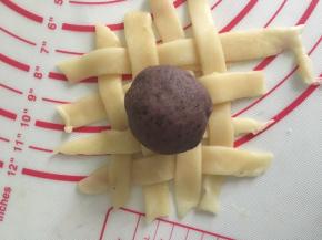 豆沙分成15份搓圆备用，取一份放在上面，包裹住豆沙收口