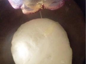 将面粉和糖倒入酵母水中，用筷子搅拌一下，开始揉面，揉至“三光”，倒入油，接着揉。