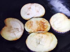 开大火置锅，锅热放油，油量和平时炒菜油差不多，油热后改中火，放入几片茄子煎制。