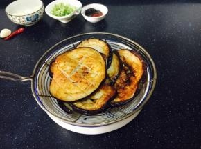 煎好的茄子片用篦网沥一下油