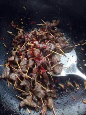 把多余的油倒出来剩一点再重新加热，放入大蒜辣椒姜丝翻炒一下，然后倒入牙签肉中火翻炒三分钟左右，加入少许酱油鸡精就可以出锅了，有香菜的还可以放一点提味