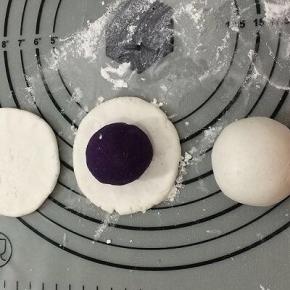 拿一个面团，用手挰成中间厚四周薄的饼，然后将紫薯球放在饼中间，用手一点点的将紫薯球包入，不要将紫薯馅露出