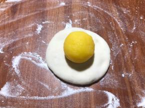 把醒好的面团揉光滑，按扁，包裹馅球。