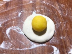 把醒好的面团揉光滑，按扁，包裹馅球。