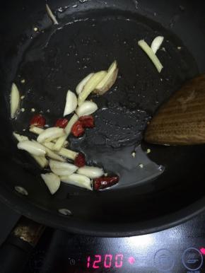 7. 炒锅注入少许花生油，把姜丝，蒜瓣，干辣椒煸香