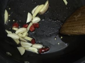 7. 炒锅注入少许花生油，把姜丝，蒜瓣，干辣椒煸香