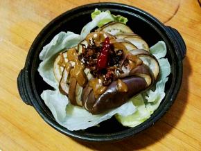 取出熟了的茄子，容器下垫上生菜，将调好的麻酱淋到茄子上，再放上拍碎的蒜蓉和菌子油。吃时拌匀即可。