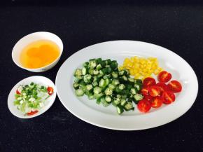 秋葵洗干净，焯水，切除秋葵老梗，秋葵切成1厘米的段。
玉米煮熟，剥粒。
小番茄一切为二。
鸡蛋打散备用。
小香葱切成葱花。