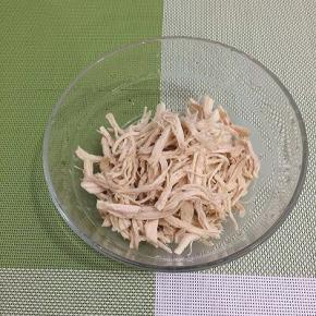 鸡胸肉晾凉，戴上一次性手套，将鸡胸肉撕成丝，装入碗中